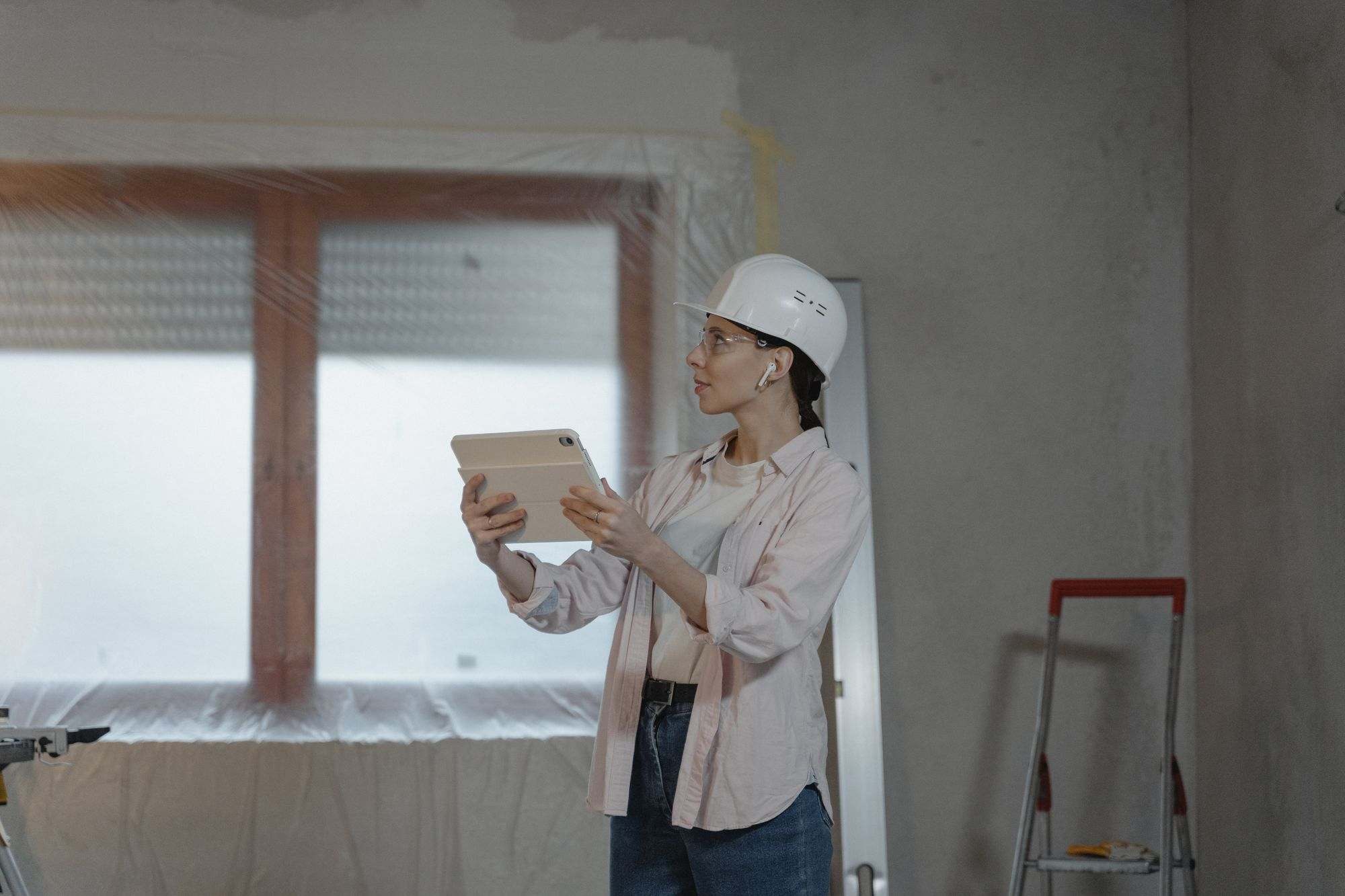 Kỹ sư đội mũ bảo hộ cầm máy tính bảng trong căn nhà đang thi công